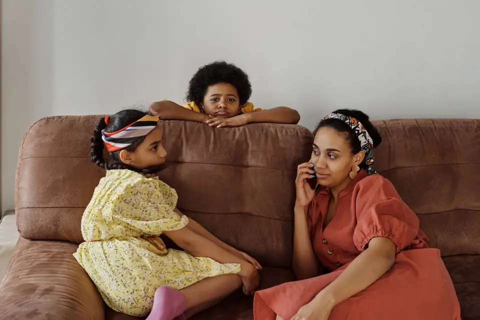 A parent looking at a phone with a child beside them